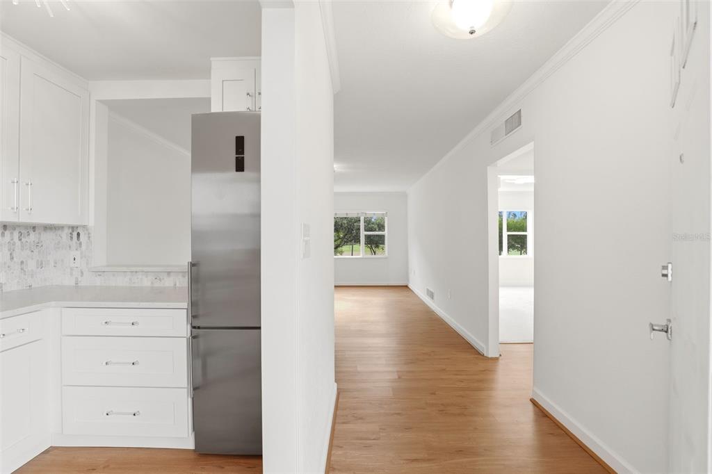 A view from a white kitchen with stainless steel appliances into a bright living area — 640 N PARK AVENUE UNIT 5, WINTER PARK, FL
