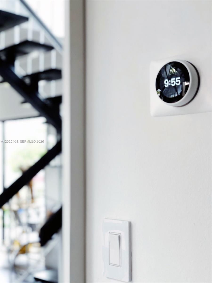 A wall-mounted smart thermostat and a light switch are visible next to a staircase — MIAMI, FL