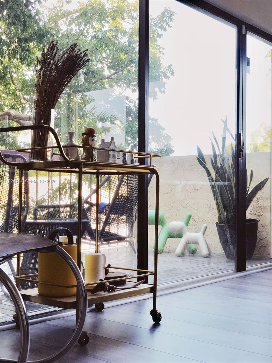 A gold bar cart sits in a room with large sliding glass doors leading to a patio — MIAMI, FL