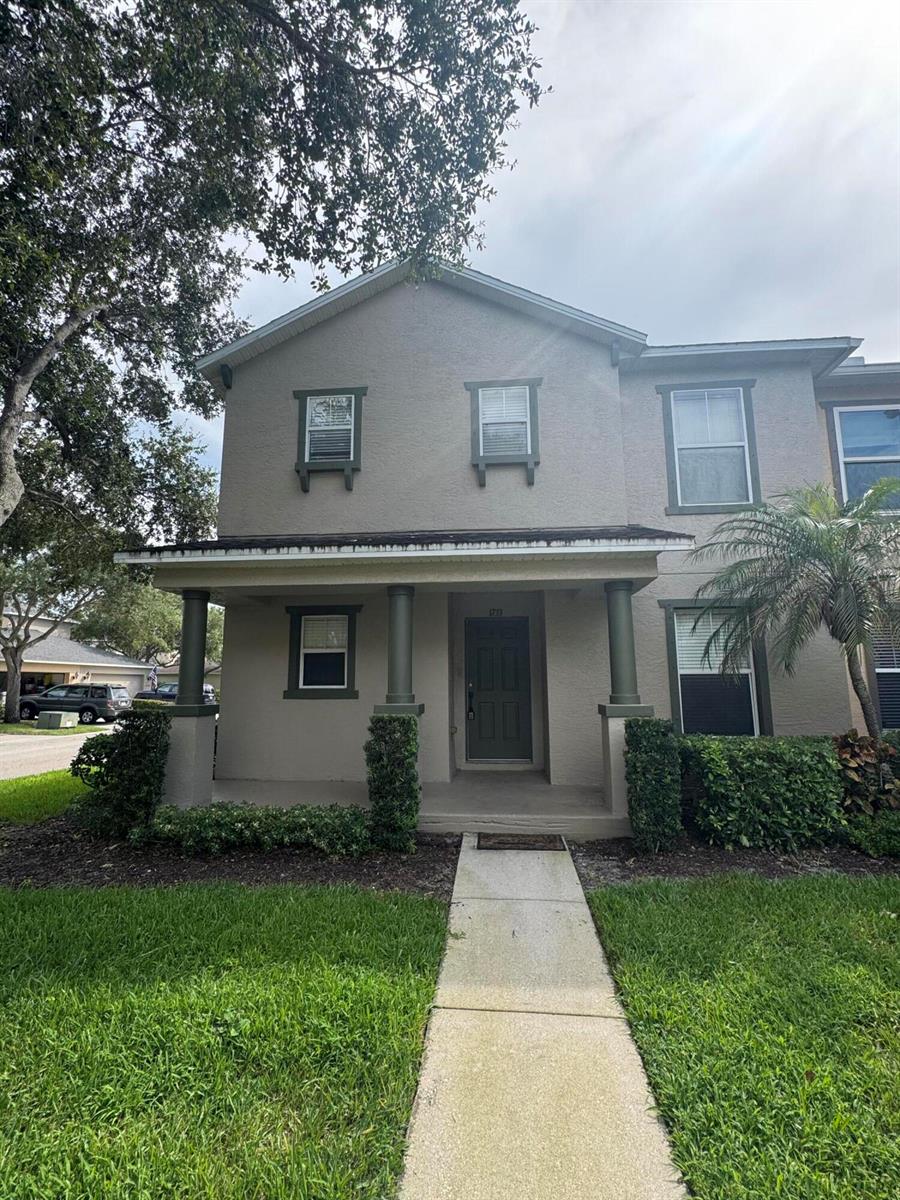 A two-story tan townhouse features a covered front porch with columns and a walkway — 1733 Pointe West Way, Vero Beach FL 32966, VERO BEACH, FL