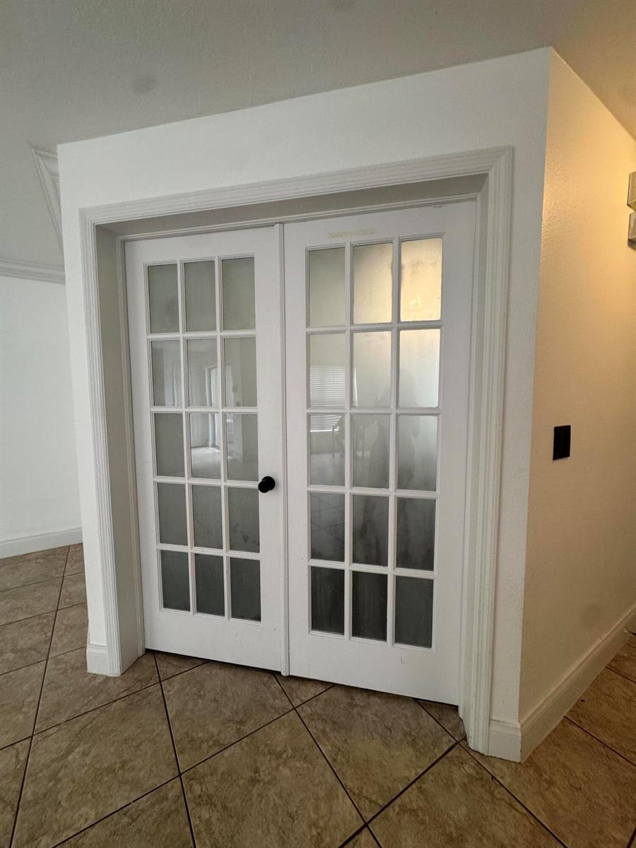 White French doors with glass panes are set into a wall with tiled flooring — 1733 Pointe West Way, Vero Beach FL 32966, VERO BEACH, FL