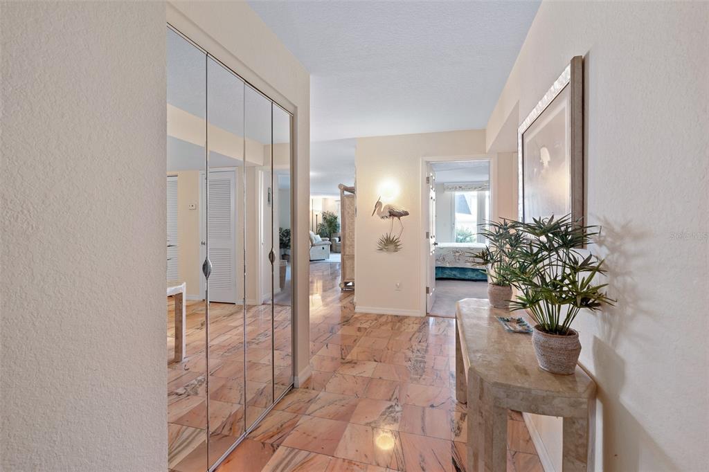 A hallway with marble flooring, mirrored closet doors, and a console table with a plant — 395 S ATLANTIC AVENUE UNIT 102, ORMOND BEACH, FL
