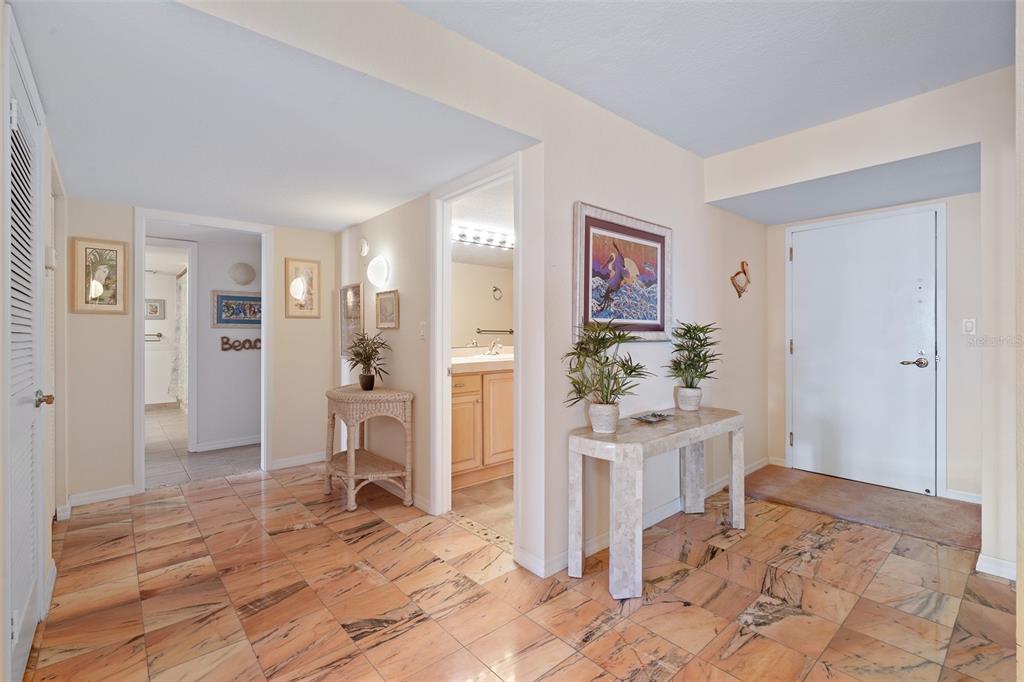 An entryway with marble tile flooring, a white front door, and two console tables — 395 S ATLANTIC AVENUE UNIT 102, ORMOND BEACH, FL
