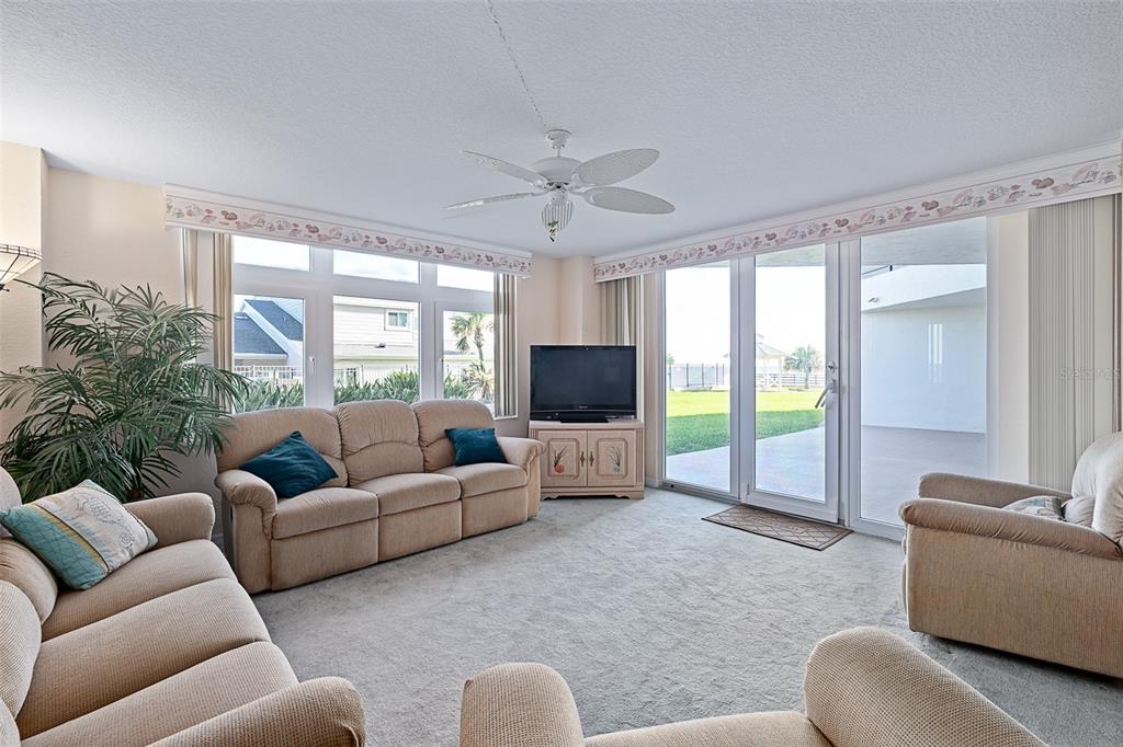 A living room features beige furniture, a ceiling fan, and sliding glass doors to a patio — 395 S ATLANTIC AVENUE UNIT 102, ORMOND BEACH, FL