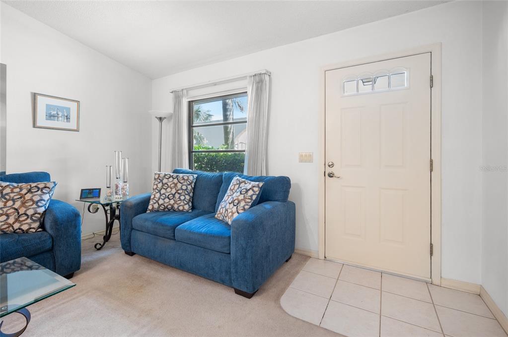 A living room features blue sofas, a glass-topped table, a window, and a front door — 221 HIGH POINT DRIVE UNIT 221A, ENGLEWOOD, FL