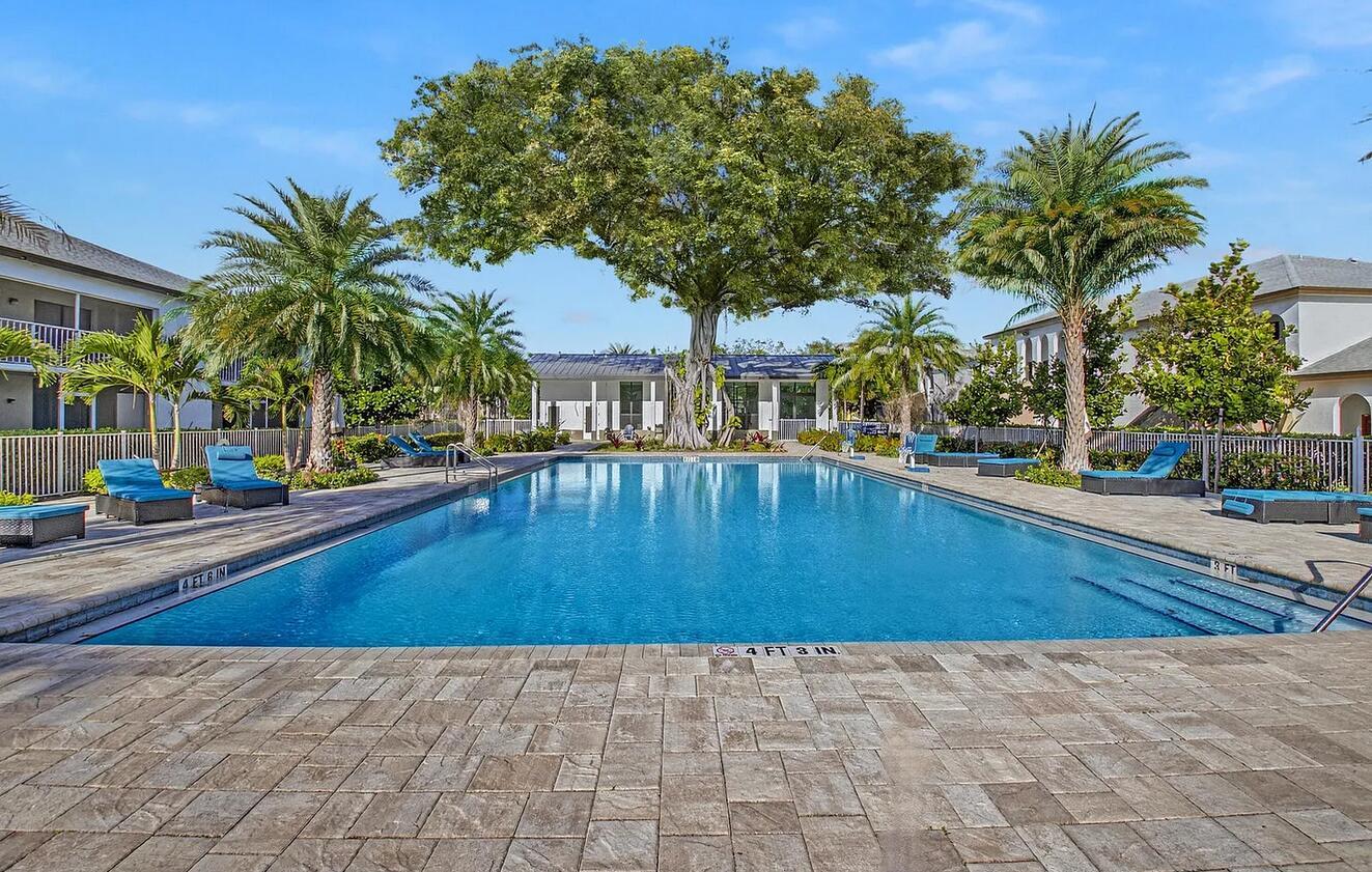 A rectangular swimming pool is surrounded by a stone patio, palm trees, and lounge chairs — 100 W Hidden Valley Boulevard # 302, Boca Raton FL 33487, BOCA RATON, FL