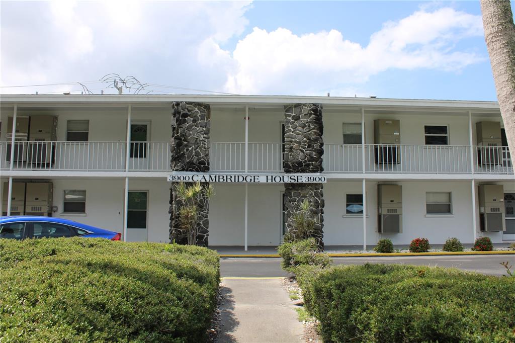 A two-story apartment building features white walls, stone pillars, and an exterior walkway — 3900 ROXANE BOULEVARD UNIT 10B, SARASOTA, FL