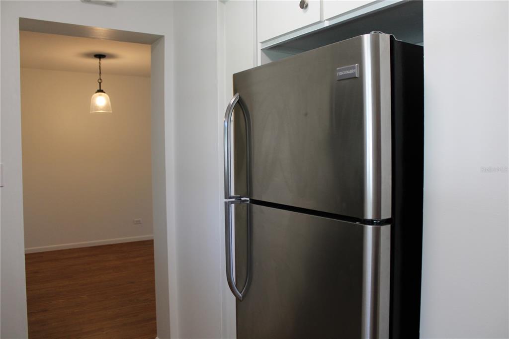 A stainless steel Frigidaire refrigerator stands in a kitchen next to a doorway leading inside — 3900 ROXANE BOULEVARD UNIT 10B, SARASOTA, FL
