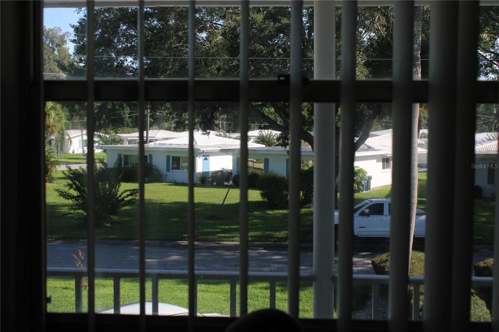 A view of a residential street and houses seen through vertical window blinds — 3900 ROXANE BOULEVARD UNIT 10B, SARASOTA, FL