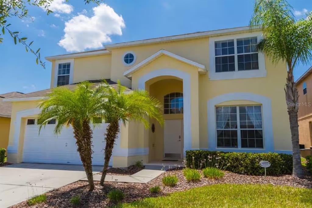 A two-story yellow house with a two-car garage and a palm tree in the front — 182 HIDEAWAY BEACH LANE, KISSIMMEE, FL