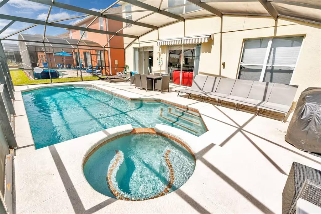 A screened-in patio features a swimming pool, a circular spa, and outdoor dining furniture — 182 HIDEAWAY BEACH LANE, KISSIMMEE, FL