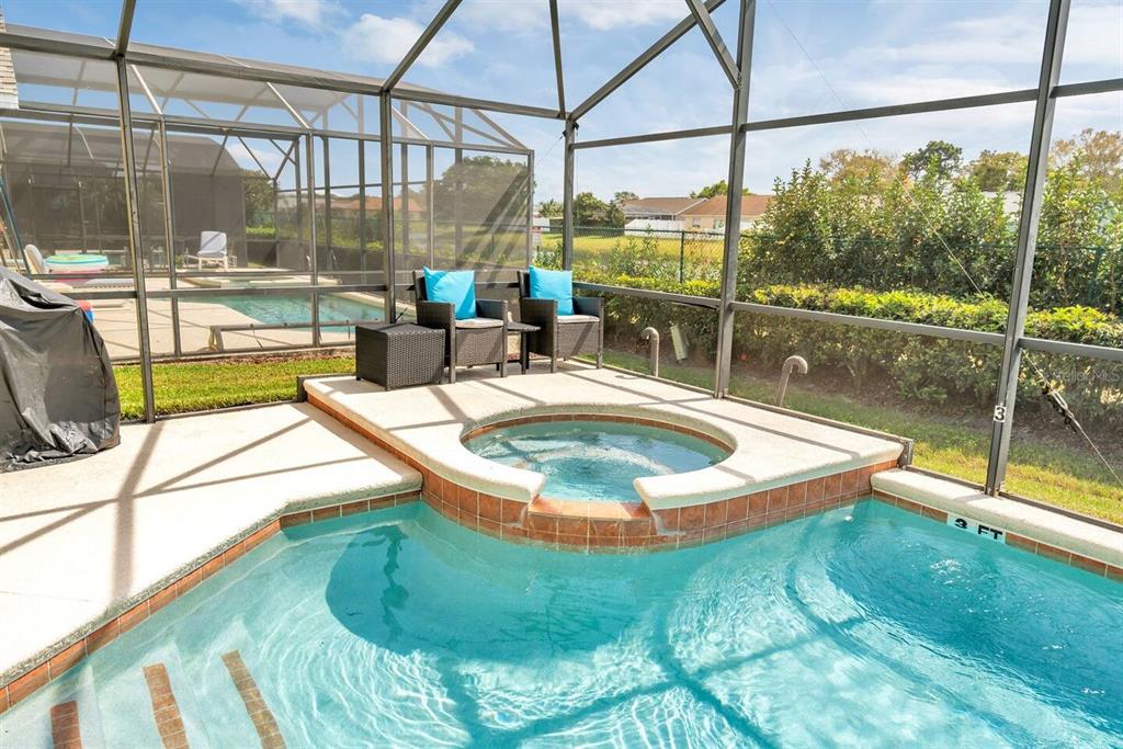 A screened-in patio features a swimming pool with an integrated raised hot tub — 182 HIDEAWAY BEACH LANE, KISSIMMEE, FL