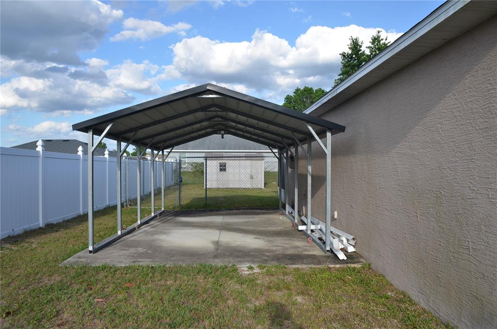 A metal carport stands on a concrete slab next to a house with a fence — 13785 SW 42ND COURT ROAD, OCALA, FL
