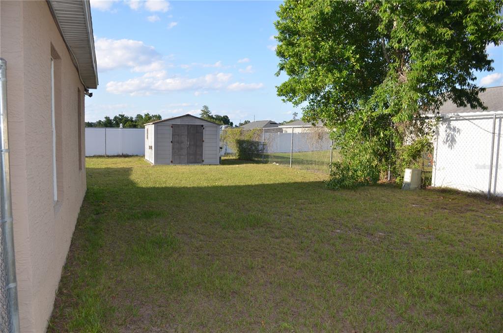 A backyard features a grassy lawn, a storage shed, and a chain-link fence — 13785 SW 42ND COURT ROAD, OCALA, FL