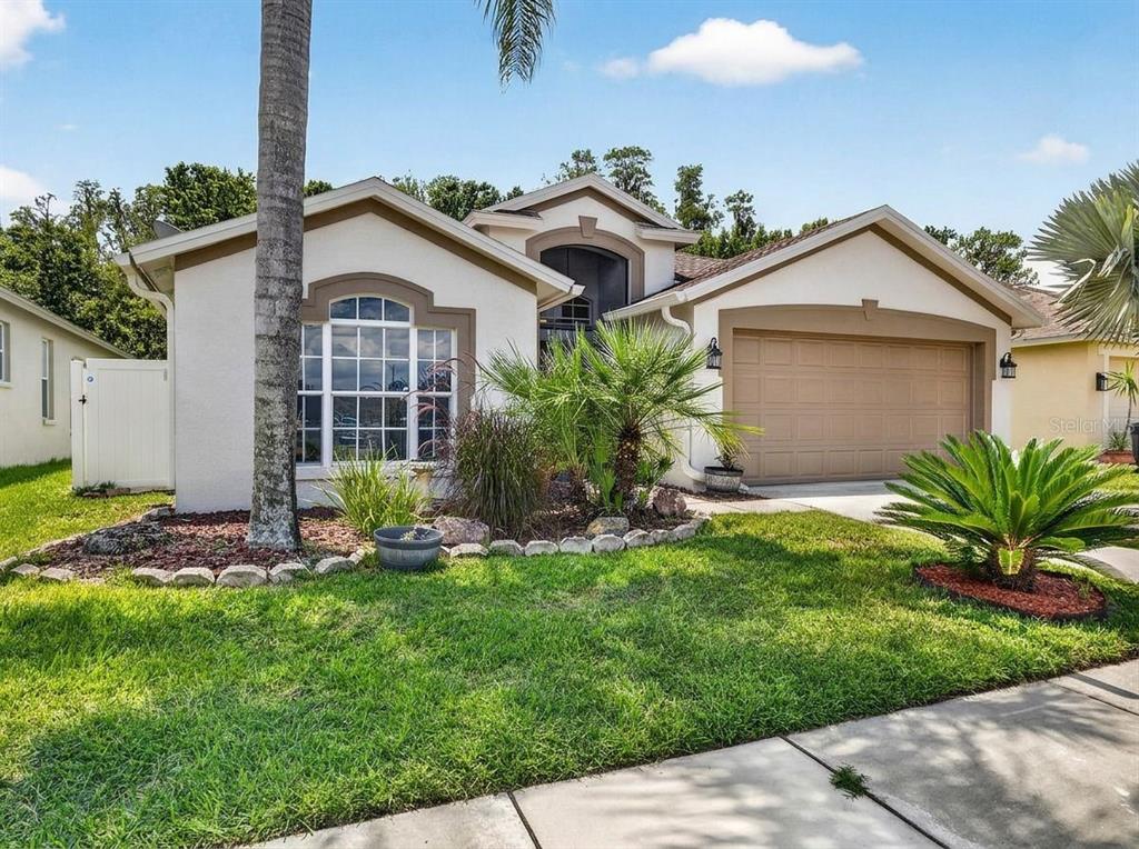 A single-story house with a beige stucco exterior, a two-car garage, and a front lawn — 29454 CROSSLAND DRIVE, WESLEY CHAPEL, FL