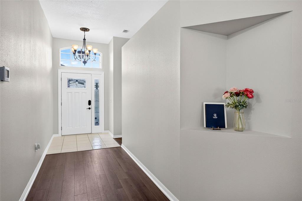 A foyer features a white front door, tile entryway, dark wood flooring, and a recessed wall niche — 29454 CROSSLAND DRIVE, WESLEY CHAPEL, FL