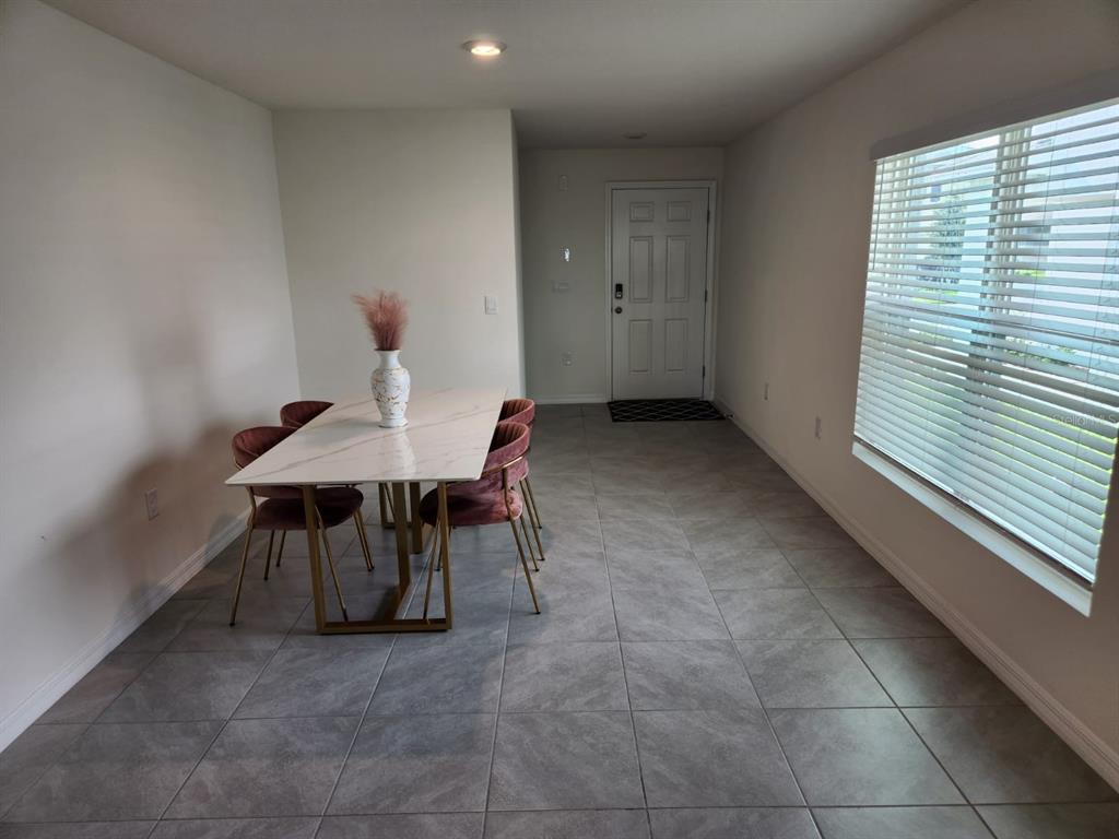 A dining area features a marble-topped table with pink chairs on gray tile flooring — 16630 MOSAIC OAR DRIVE, WIMAUMA, FL