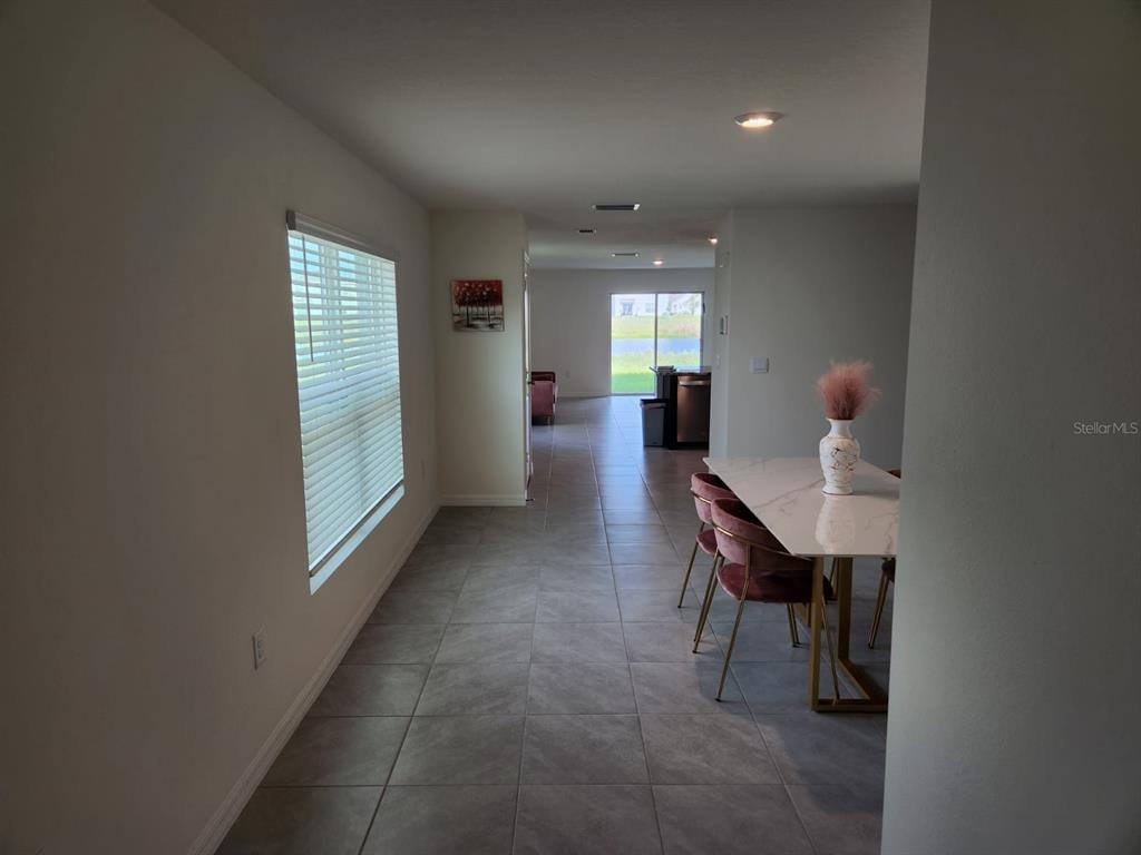 A dining area with a marble-topped table and pink chairs leads to a rear sliding door — 16630 MOSAIC OAR DRIVE, WIMAUMA, FL