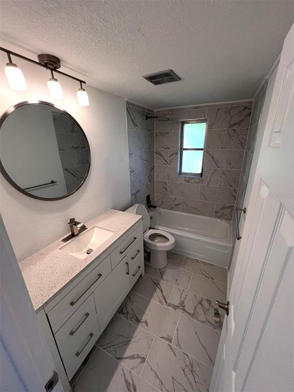 A bathroom features a vanity with a stone countertop, a round mirror, and marble-look tile flooring — 457 GARFIELD AVE NW AVENUE NW, PORT CHARLOTTE, FL