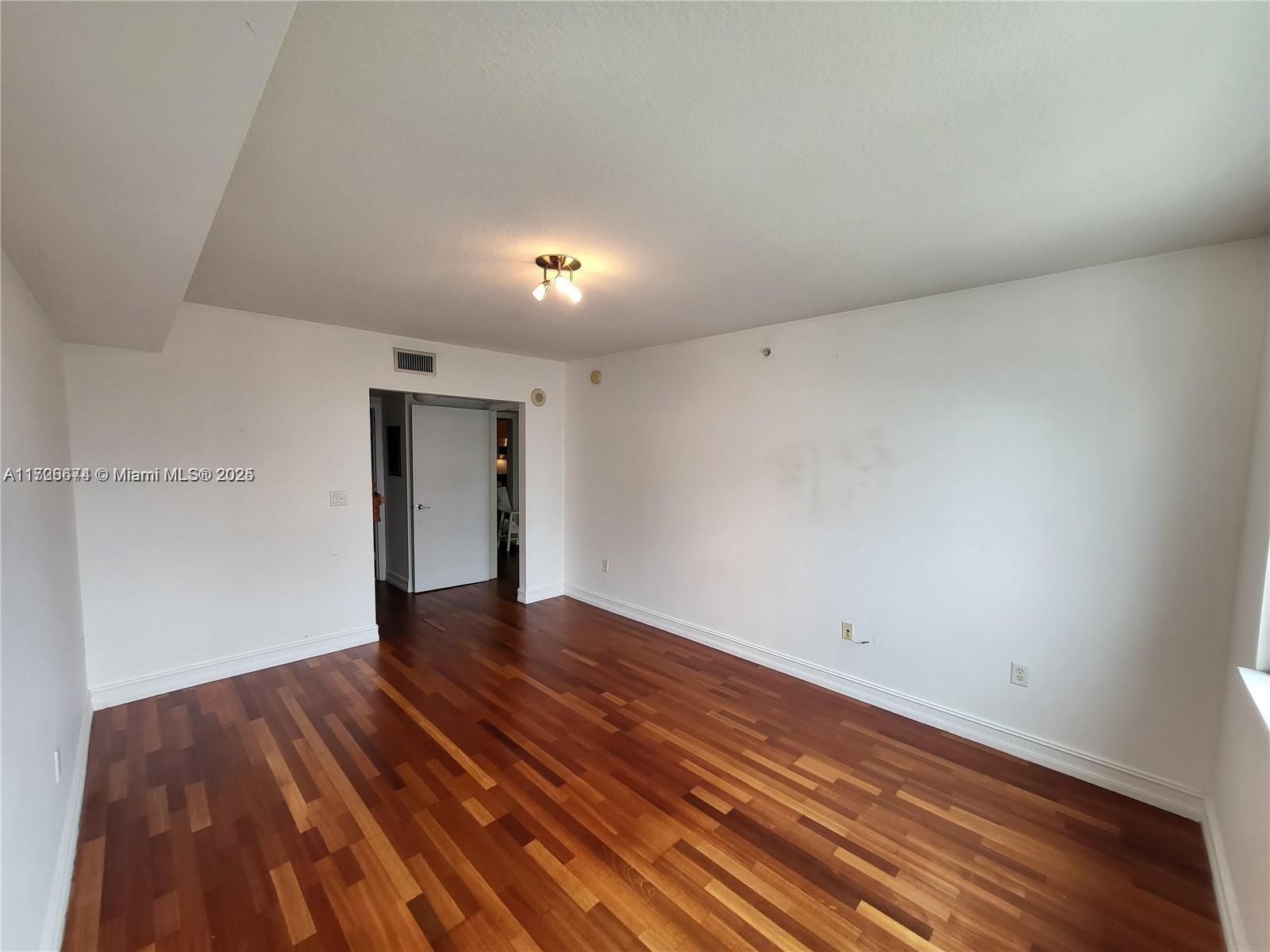 An empty room features white walls, dark wood flooring, and a central ceiling light fixture — 31 SE 5th St # 2409, Miami FL 33131, MIAMI, FL