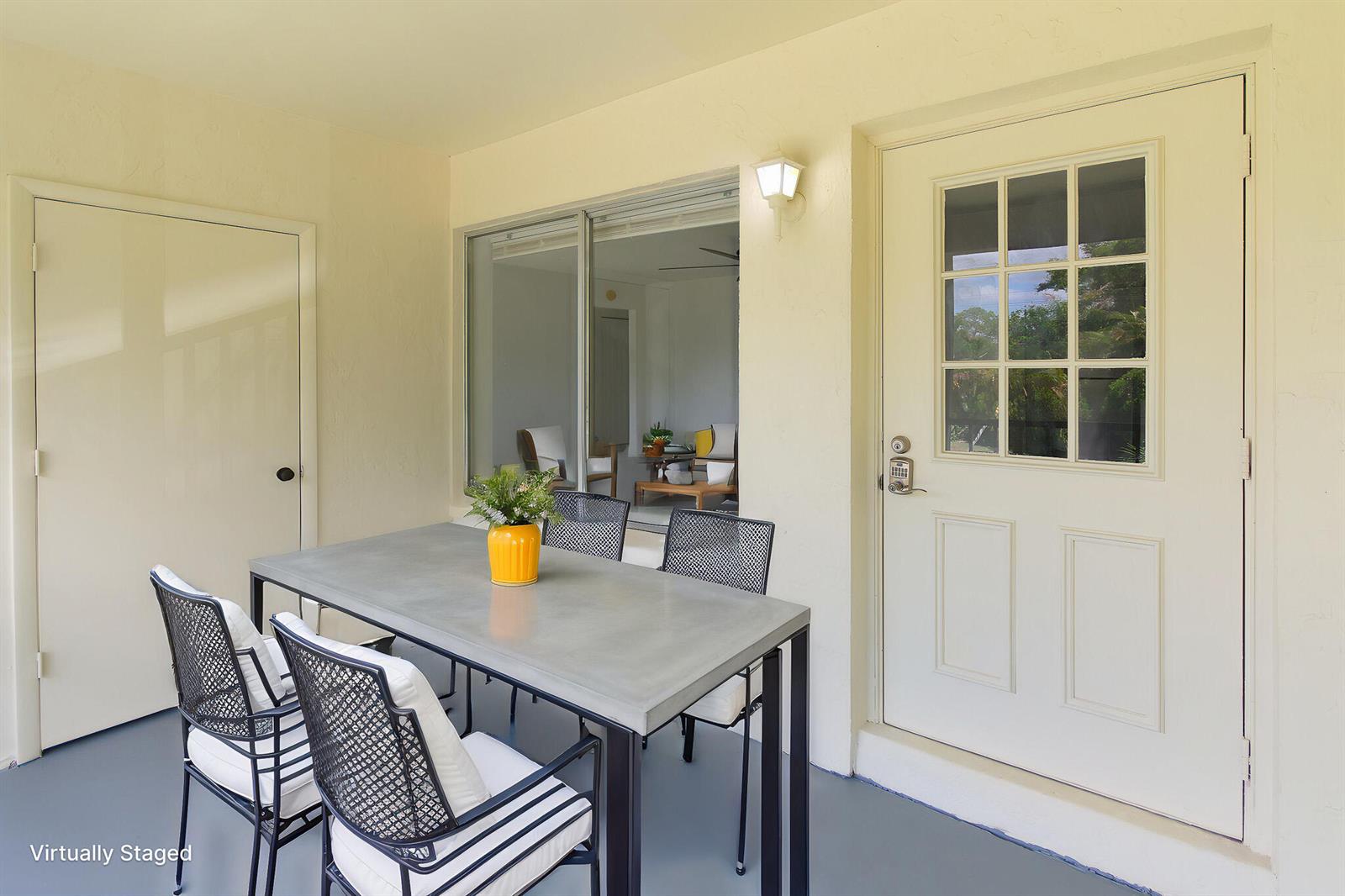 A covered patio features a concrete dining table with four chairs and a glass-paned door — 4899 Sable Pine Circle # A2, West Palm Beach FL 33417, WEST PALM BEACH, FL