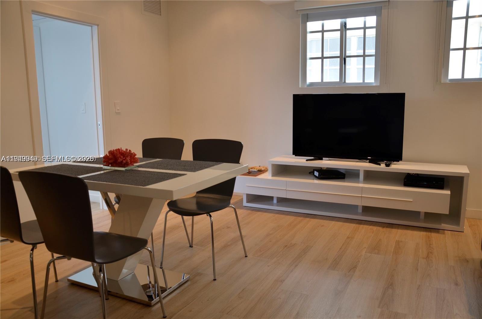 A dining area features a white table with dark chairs and a white media console — 700 16th St # 201, Miami Beach FL 33139, MIAMI BEACH, FL