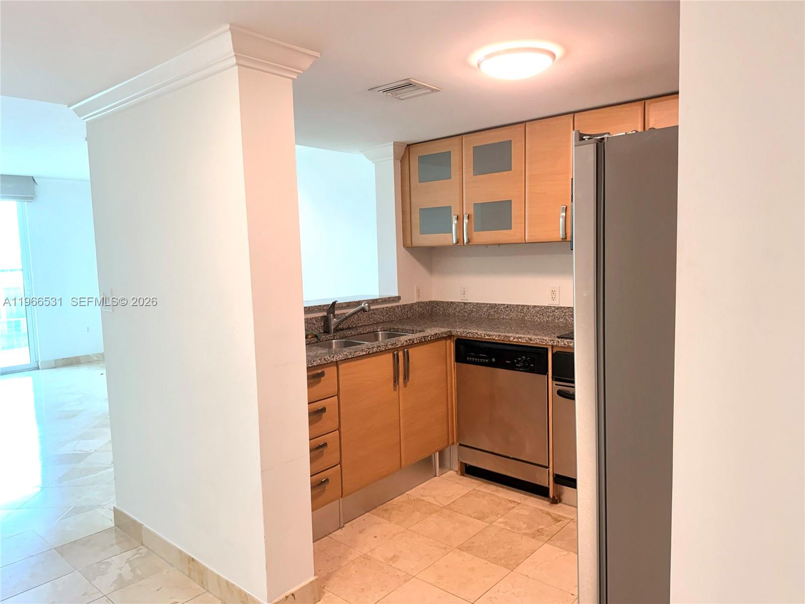 A kitchen features light wood cabinets, granite countertops, stainless steel appliances, and tile flooring — 2101 Brickell Ave # 2202, Miami FL 33129, MIAMI, FL