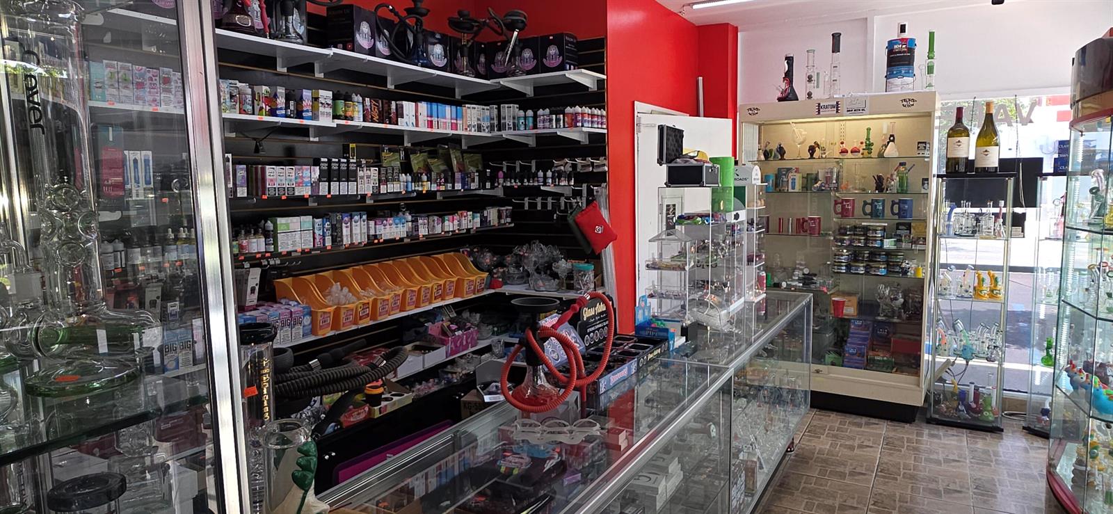 The interior of a retail smoke shop features glass display cases and shelves stocked with merchandise — 580 S Federal Highway, Pompano Beach FL 33062, POMPANO BEACH, FL