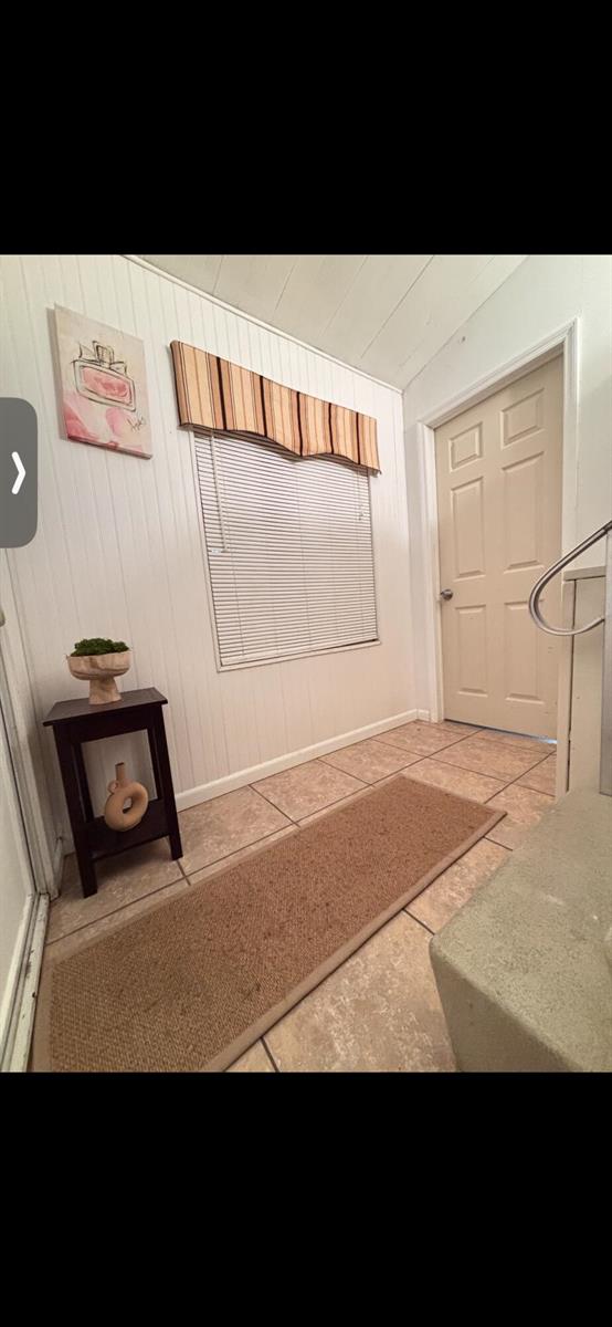 An entryway features white beadboard walls, tile flooring, a window with a valance, and a door — 875 NE 48th Street # 186, Deerfield Beach FL 33064, DEERFIELD BEACH, FL