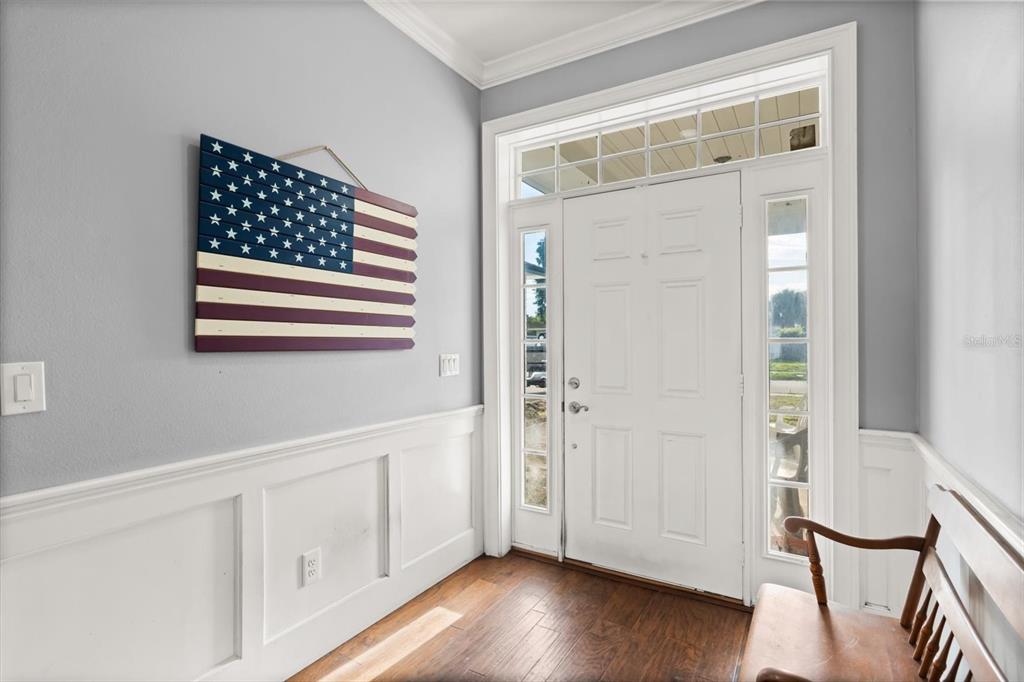 An entryway features hardwood floors, white wainscoting, a wooden American flag, and a white door — 621 PRAIRIE LANE, ALTAMONTE SPRINGS, FL