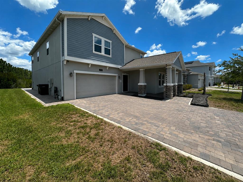 A two-story house with blue siding, a stone-accented porch, and a paved driveway — 2721 CAMDEN LANE, DAVENPORT, FL