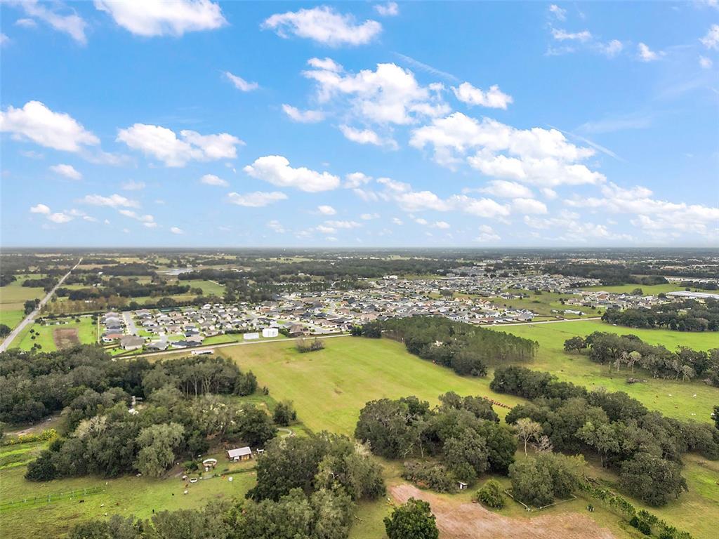 An aerial view shows a residential neighborhood surrounded by open fields and patches of trees — SUMTER COUNTY ROAD 214, OXFORD, FL