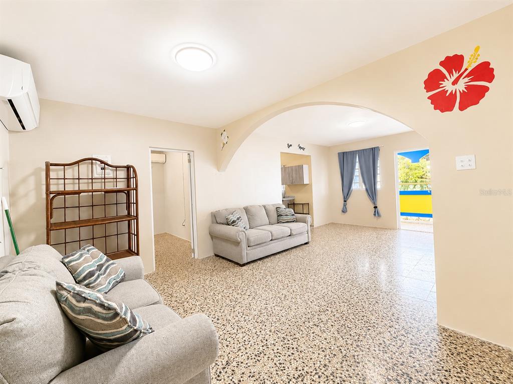 A living room with two grey sofas, a wooden shelf, and a large arched entryway — 122 Pomarosa St. URB. SAN PEDRO, FAJARDO, PR