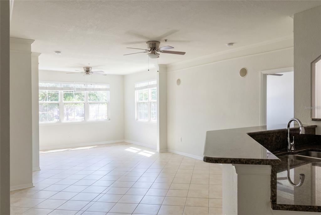 An open-concept room features light tile flooring, two ceiling fans, and a kitchen breakfast bar — 3344 CORONA VILLAGE WAY UNIT 205, ORLANDO, FL