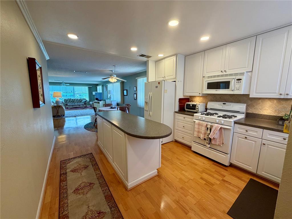 A kitchen with white cabinets and a center island opens into a living room area — 6025 SHORE BOULEVARD S UNIT 415, GULFPORT, FL