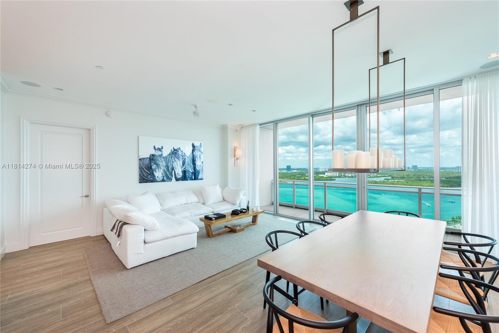 A bright living and dining area features white furniture, wood flooring, and floor-to-ceiling windows — 10295 Collins Ave # 2506, Bal Harbour FL 33154, BAL HARBOUR, FL