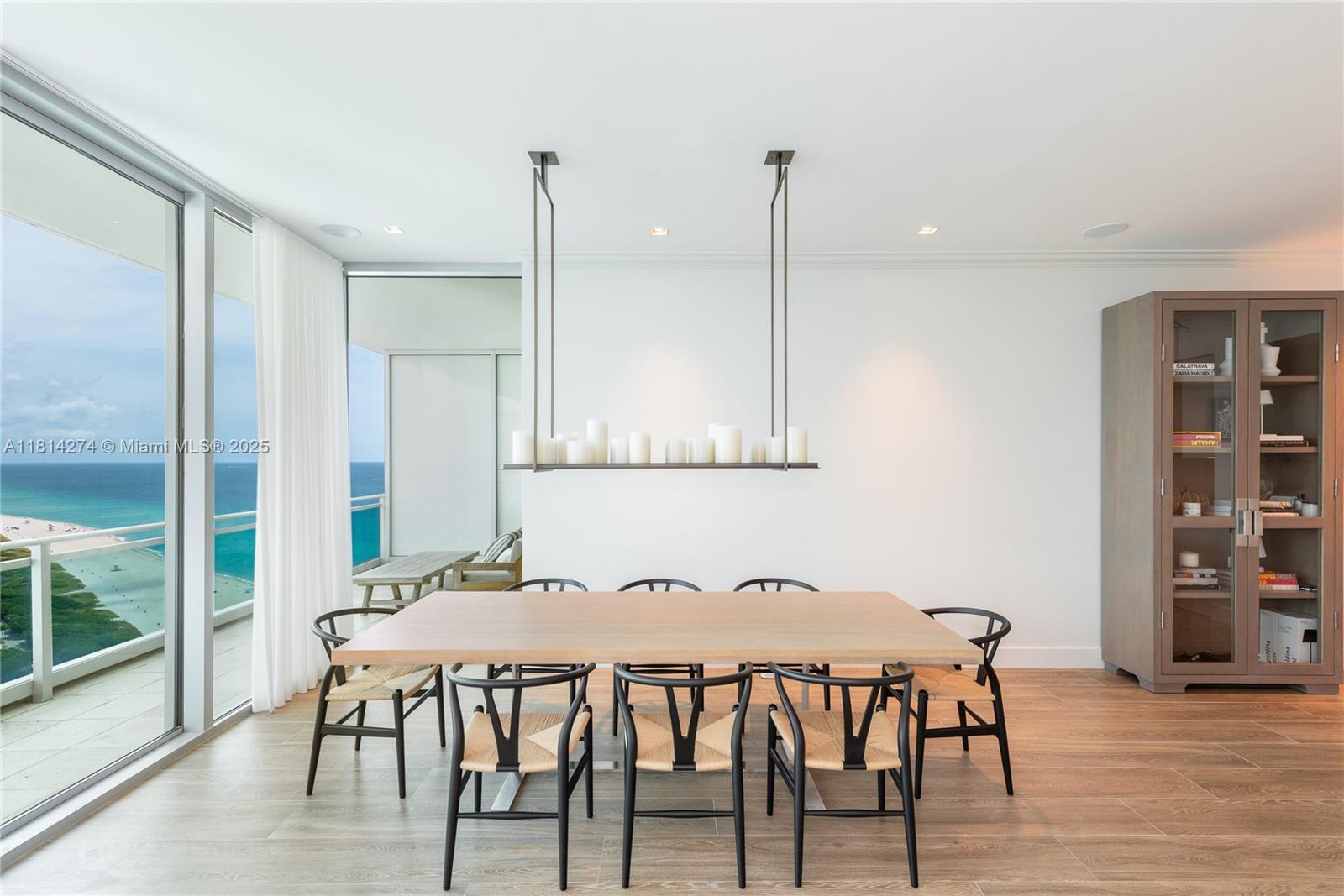 A dining room features a wooden table, black chairs, a candle chandelier, and ocean views — 10295 Collins Ave # 2506, Bal Harbour FL 33154, BAL HARBOUR, FL