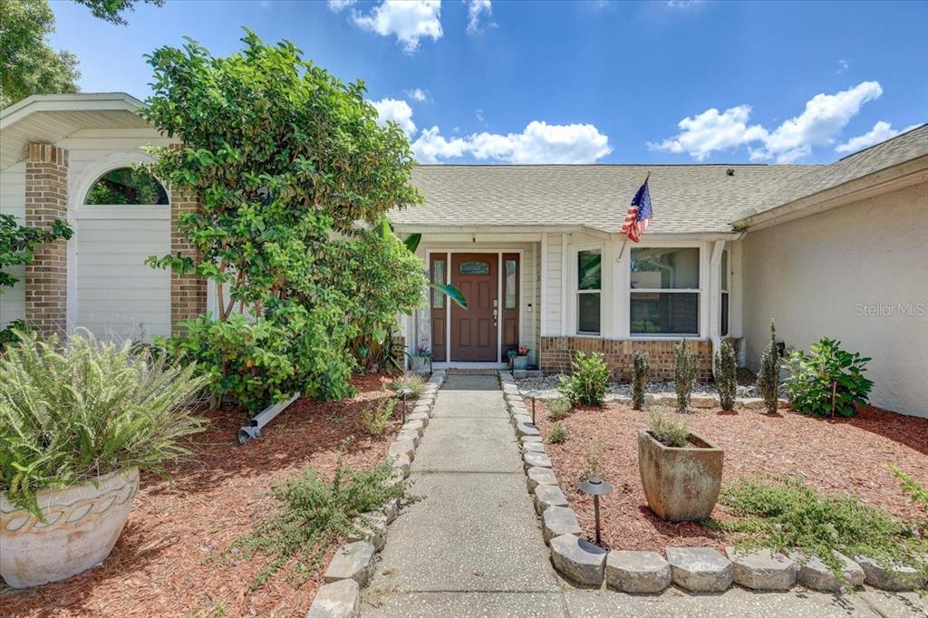 A concrete walkway leads to the front entrance of a single-story home with landscaping — 1907 HORSESHOE DRIVE, PLANT CITY, FL