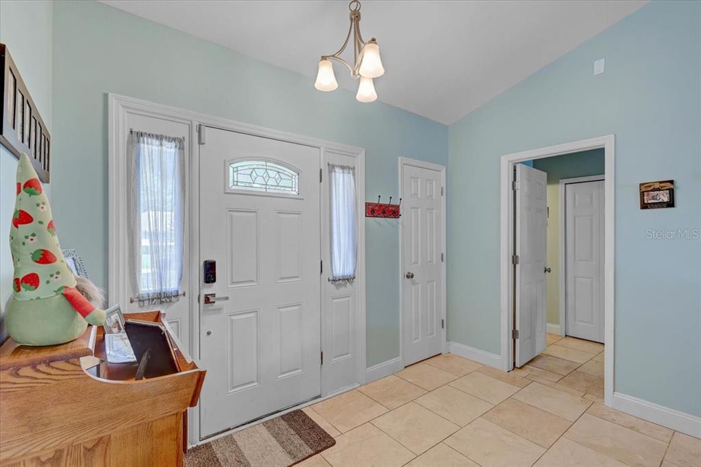 This entryway features light blue walls, tile flooring, a white front door, and a chandelier — 1907 HORSESHOE DRIVE, PLANT CITY, FL