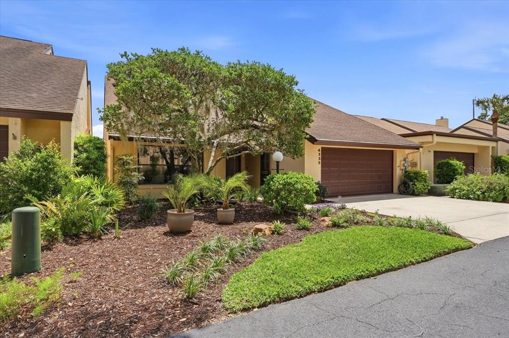 A single-story house with a brown roof, tan siding, and a two-car garage — 4135 CREEKWOOD LANE, MULBERRY, FL