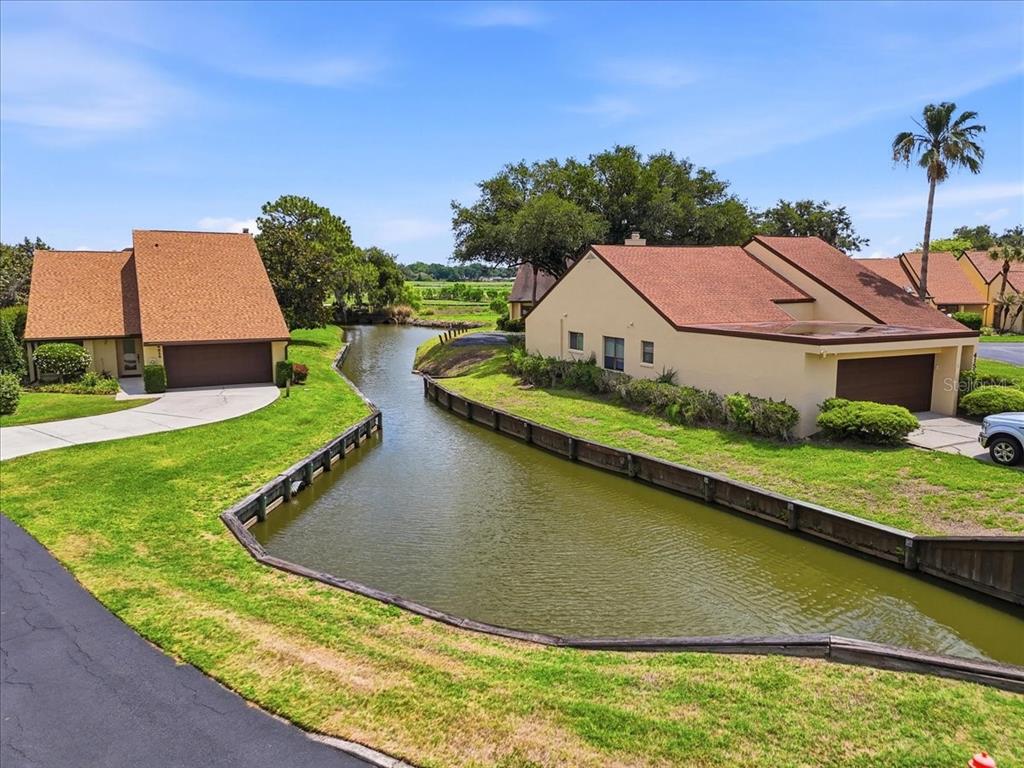 An elevated view of two houses separated by a narrow canal with wooden retaining walls — 4135 CREEKWOOD LANE, MULBERRY, FL