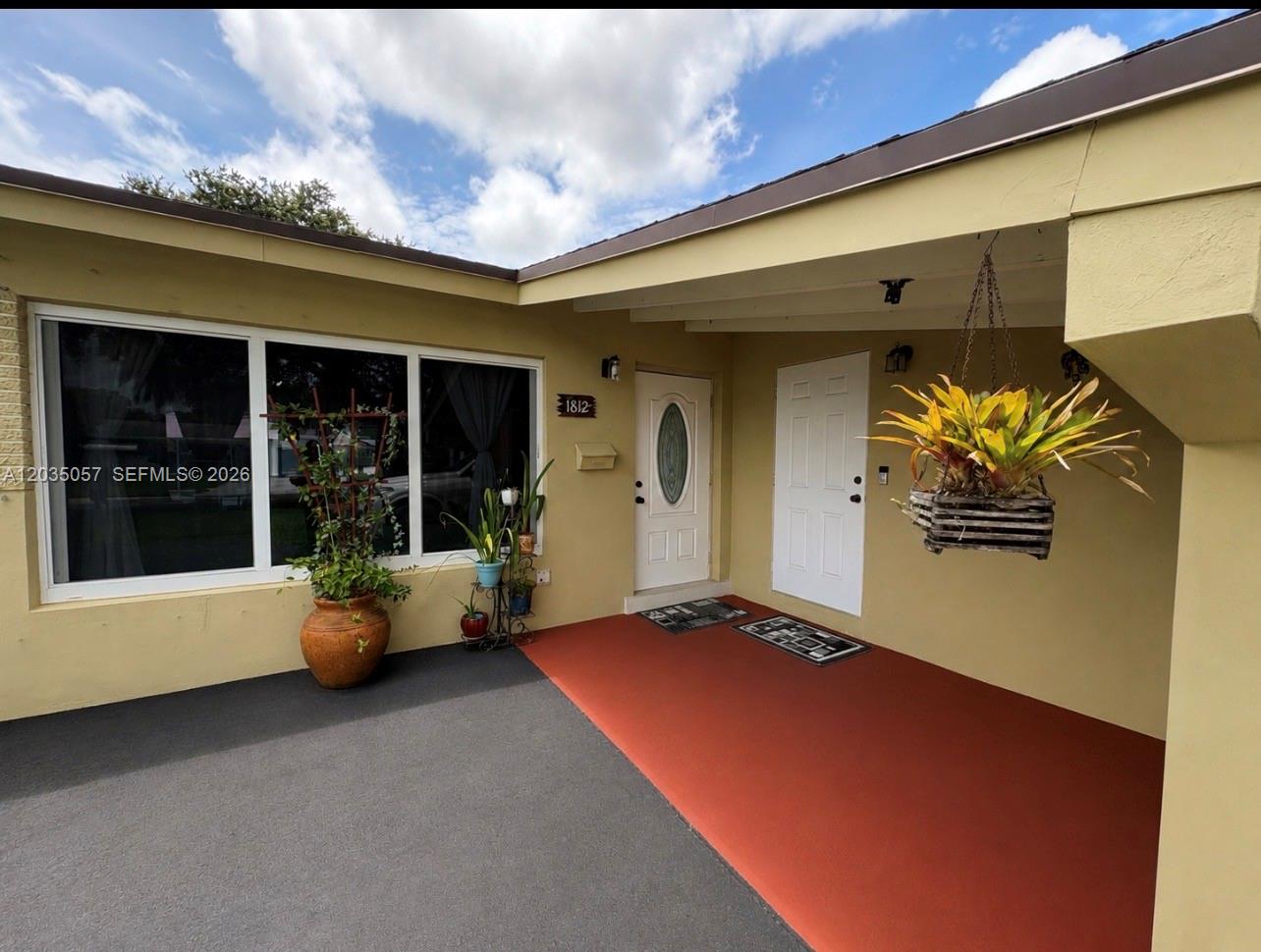 The exterior entrance features a covered porch with two white doors and potted plants — 1812 N 45th Ave, Hollywood FL 33021, HOLLYWOOD, FL