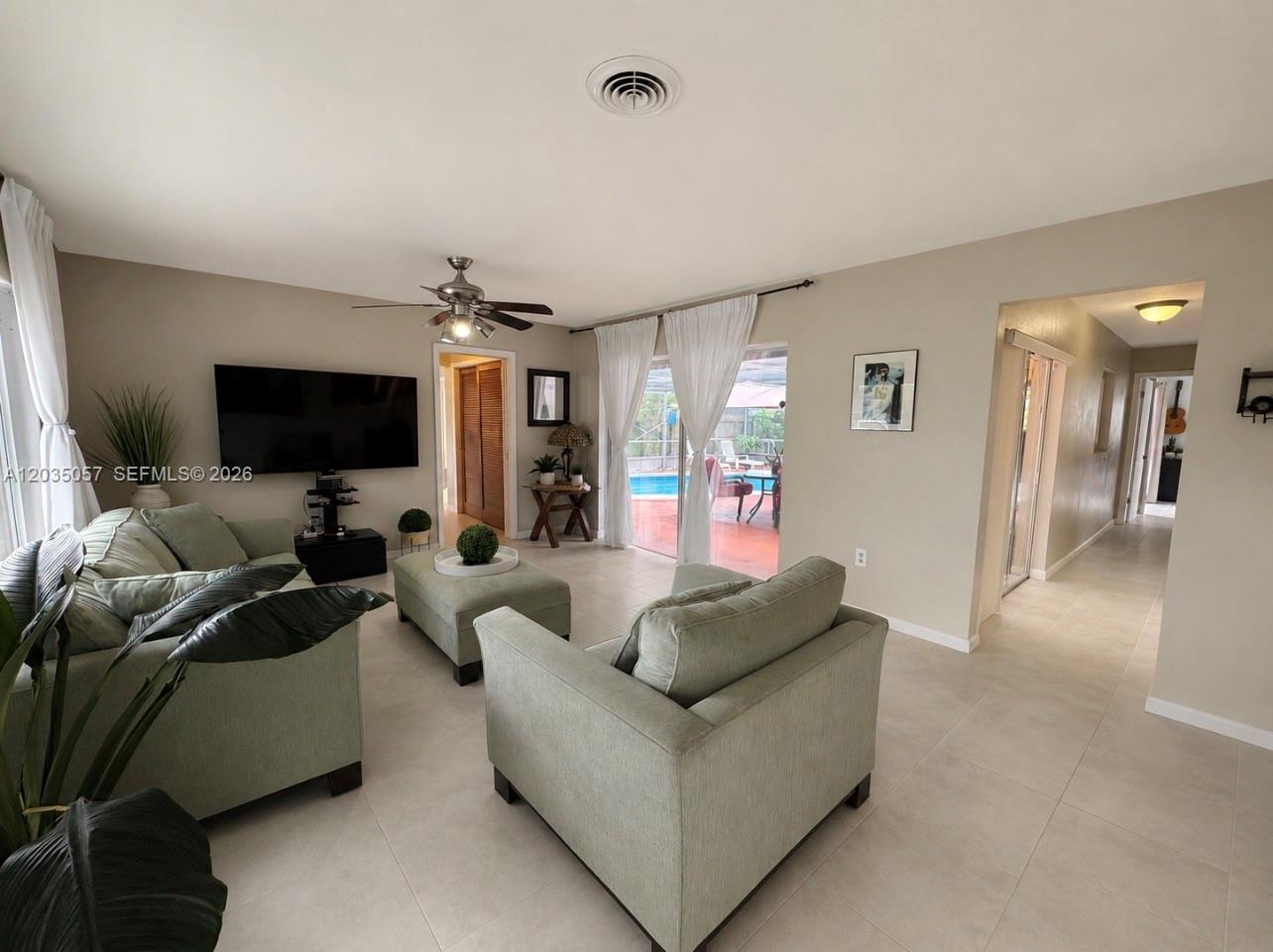 A living room features light green furniture, tile flooring, a ceiling fan, and sliding glass doors — 1812 N 45th Ave, Hollywood FL 33021, HOLLYWOOD, FL