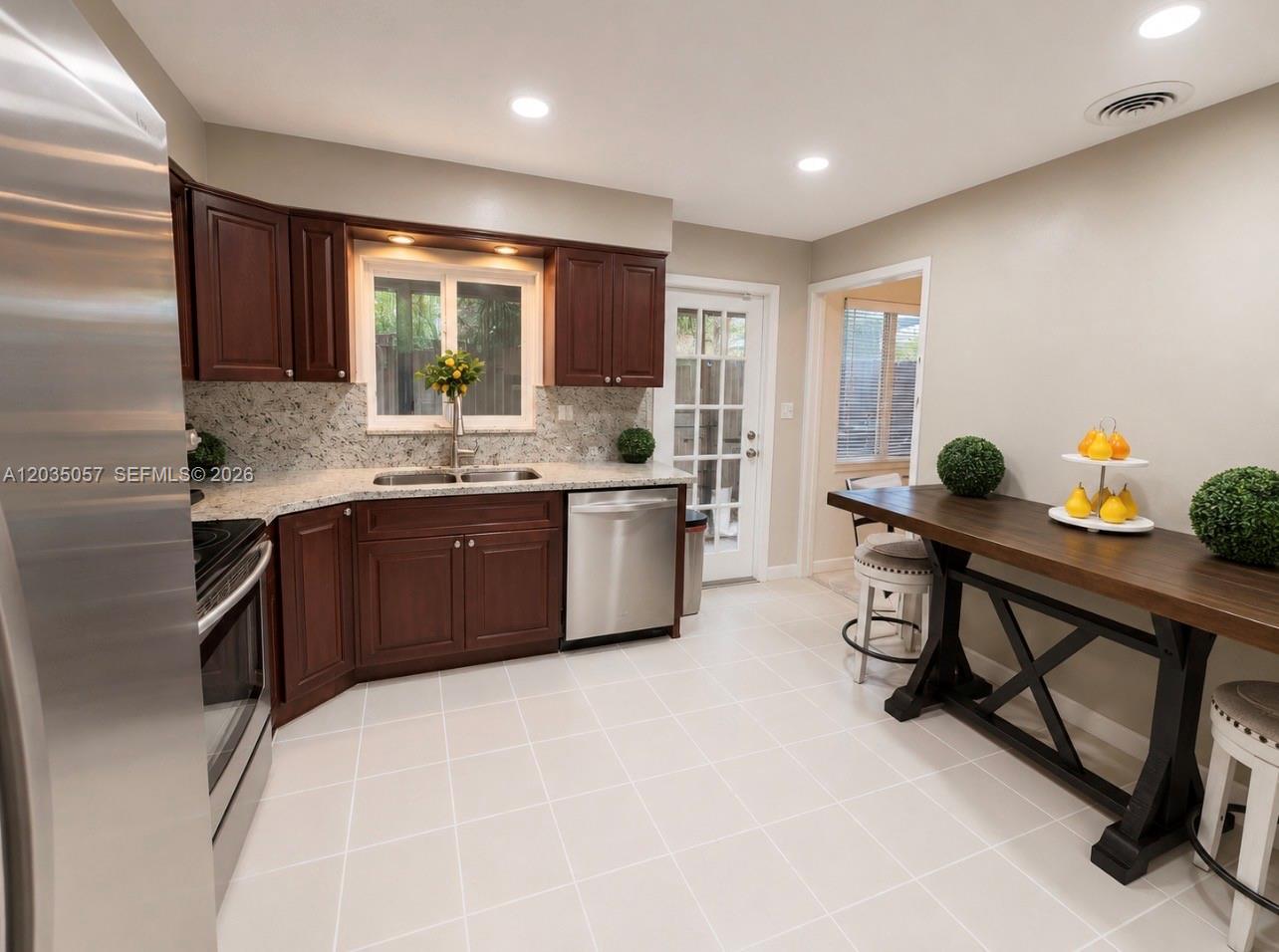 A kitchen features dark wood cabinets, granite countertops, stainless steel appliances, and a wooden island — 1812 N 45th Ave, Hollywood FL 33021, HOLLYWOOD, FL