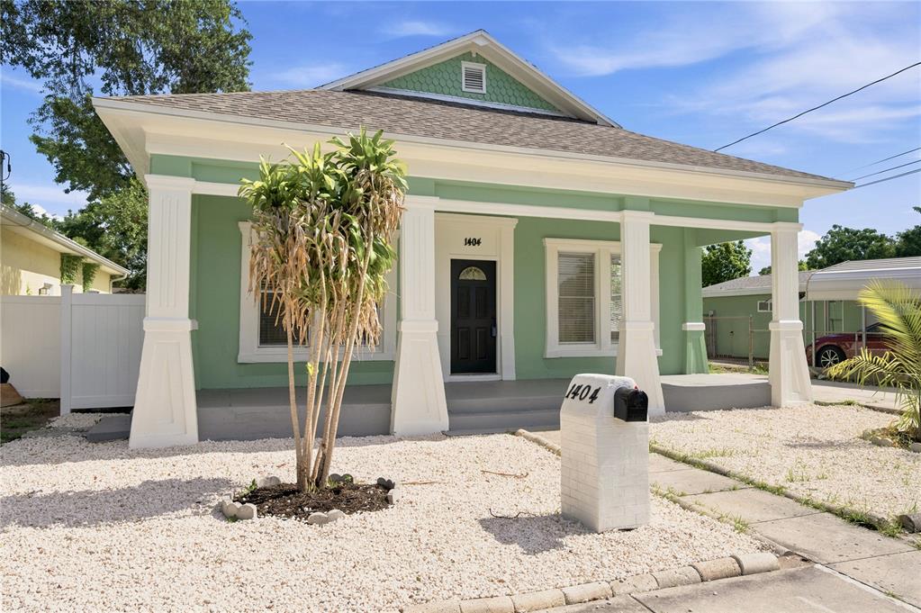 A light green single-story house with a front porch, white columns, and a gravel yard — 1404 E 26TH AVENUE, TAMPA, FL