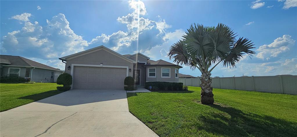A single-story house with a concrete driveway, a palm tree, and a vinyl privacy fence — 240 SOLIS DRIVE, WINTER HAVEN, FL