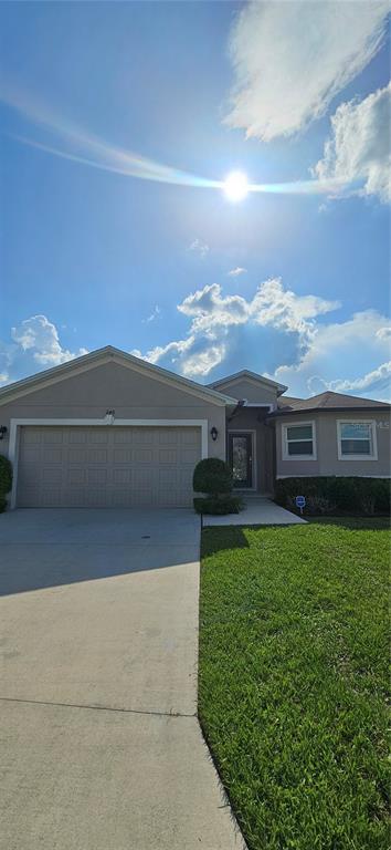 A single-story house with a beige stucco exterior, a two-car garage, and a concrete driveway — 240 SOLIS DRIVE, WINTER HAVEN, FL