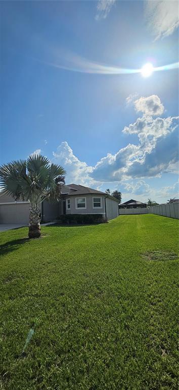 A view of a house exterior with a large lawn and a palm tree — 240 SOLIS DRIVE, WINTER HAVEN, FL