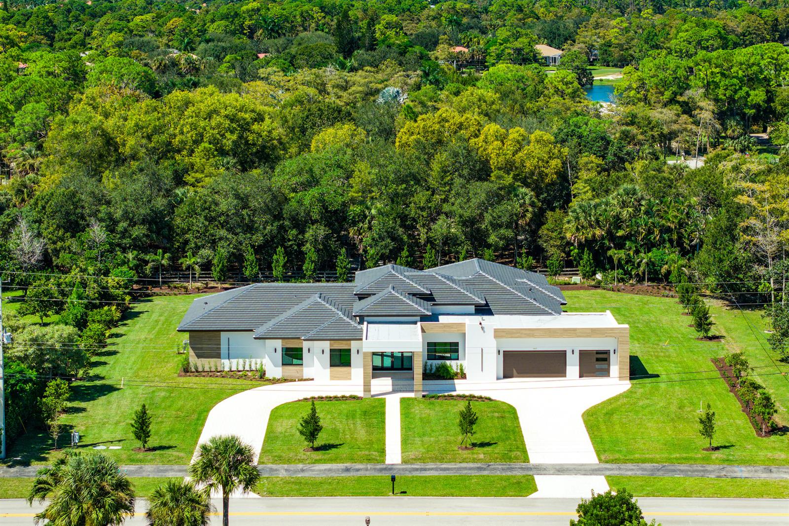 An aerial view of a modern single-story house with a dark tile roof and driveway — 14817 Paddock Drive, Wellington FL 33414, WELLINGTON, FL