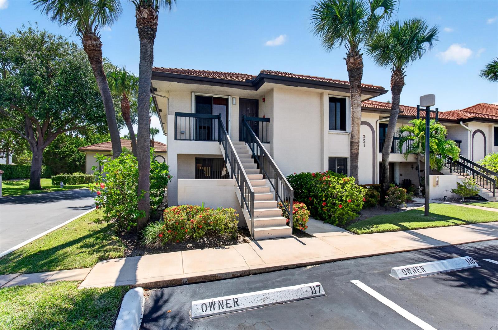 A two-story residential building features an exterior staircase leading to an upper-level unit entrance — 351 Club Circle # 101, Boca Raton FL 33487, BOCA RATON, FL
